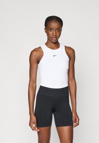 Biała bezrękawnik sportowy z małym czarnym logo Nike, połączony z czarnymi szortami Nike Pro o wysokim stanie z teksturowanym paskiem.