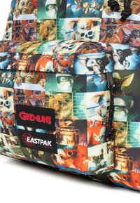 Rugzak met Gremlins-thema met een levendige fotocollage, zwarte accenten en Eastpak-branding, gemaakt van een textiel met een duurzame, gestructureerde afwerking.