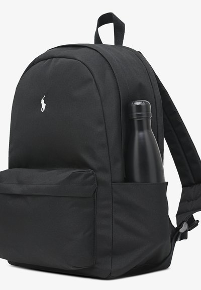 Svart ryggsäck av texturerat tyg, med en framträdande logotyp, justerbara remmar och en sidoficka som håller en svart vattenflaska.