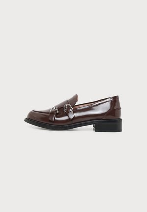 Brun læderloafer med blank finish, lav sort hæl og sølvspænde fortil, vist i profil på hvid baggrund.
