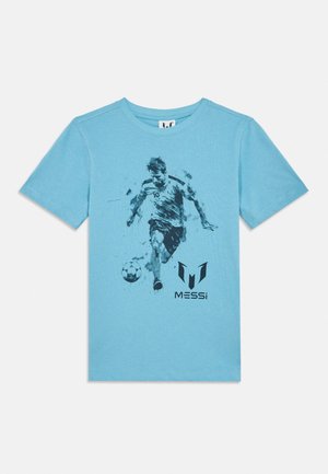 Tricou albastru deschis cu o grafică a unui jucător de fotbal cu numărul 10, care lovește o minge, și logo-ul "Messi" sub imagine.