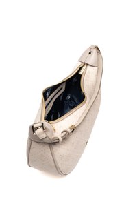 Beige handväska med en texturerad yta, rund form och guldfärgad metalldetalj. Dragkedjan avslöjar ett marinblått foder med ett subtilt mönster.