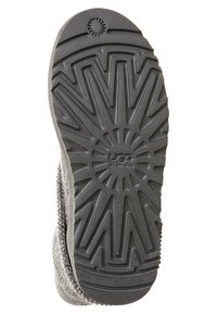 Suela de bota de goma gris con un patrón de banda de rodadura en forma de estallido y el logo "UGG Australia". Cuenta con lados texturizados y una forma de puntera redondeada.