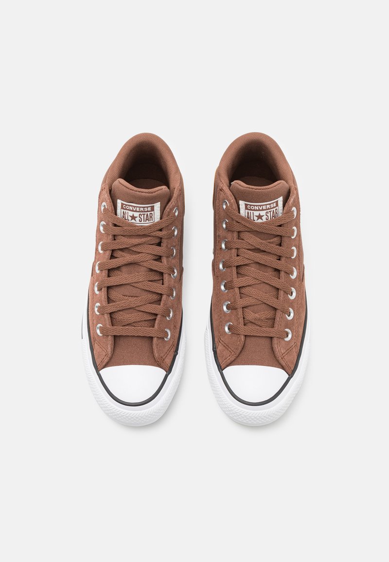 Baskets en toile marron avec embouts en caoutchouc blanc, lacets plats et œillets gris. Présente une étiquette de logo sur la languette. Design classique à tige basse.