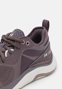 Purple athletic sneaker featuring a textured mesh upper, padded collar, and a contrasting light-colored sole with minimal branding accents.