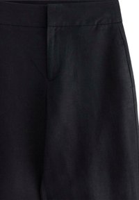 Pantalon noir à la texture lisse, avec un devant plat, une fermeture à crochet dissimulée et des poches sur les côtés. Design simple à jambe droite.
