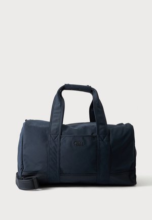 Sac polochon bleu foncé avec double poignées et sangle d'épaule, avec une petite poche avant et un logo BOSS sur un fond uni.