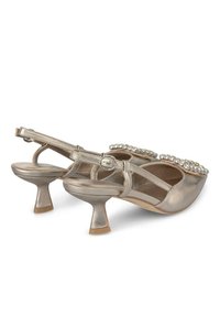 Metallic gouden slingback hakken met een middelhoge, geflardeerde hak en met juwelen versierde accenten aan de voorkant. Gladde textuur met een glanzende afwerking.