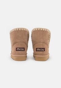Stivaletti alla caviglia in suede color sabbia con bordo intrecciato, dotati di suola in gomma piatta e un piccolo logo "mou" di colore viola scuro sul tallone.