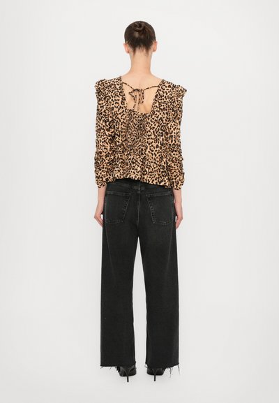 Luipaardprint blouse met geruite mouwen, open rug met strikjes, gecombineerd met hoge taille zwarte wijde broek met rafelige zoom.
