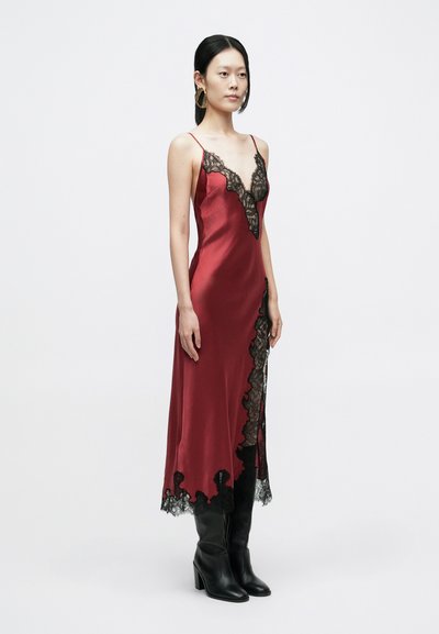 Robe nuisette en satin rouge avec bordure en dentelle noire le long de l'encolure et de l'ourlet, dotée de fines bretelles et d'une silhouette ajustée.