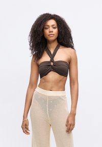 Brūns halter stila bikini tops ar izgrieztu dizainu un griezuma detaļu. Sānos ar krēmveida rakstainām, adītām augstām biksēm.