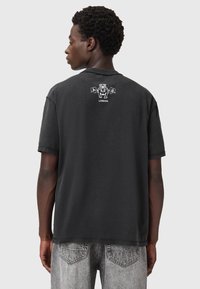 Camiseta de algodón negra de manga corta, con un diseño gráfico en la parte posterior. La textura es suave y el ajuste es relajado.
