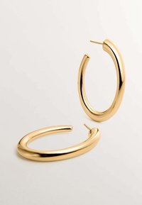 Pendientes de aro en tono dorado con un diseño suave y redondeado y un acabado pulido. Cuentan con un poste delgado y una forma circular abierta.