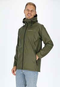 Olivgrüne, wasserdichte Jacke mit hohem Kragen, verstellbaren Zugbändern und schwarzen Reißverschlüssen. Mit einem Logo auf der Brust und elastischen Bündchen.