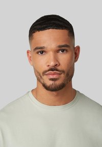 Lichtgroene crewneck t-shirt met een gladde textuur, voorzien van een ronde hals en korte mouwen, gedragen door een man met een kort geknipte haardos.