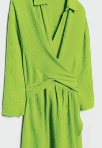 Abito verde avvolgente con collo a camicia, maniche lunghe, superficie texturizzata e vita con laccetto, caratterizzato da una silhouette fluida e gonna arricciata.
