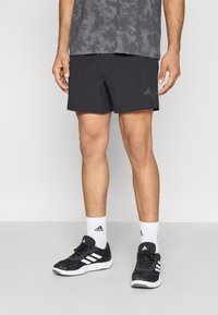 Μαύρο αθλητικό σορτς από ελαφρύ ύφασμα με απαλή υφή. Διαθέτει διακριτικό λογότυπο adidas σε σκούρο γκρι. Φοριέται με μαύρα παπούτσια.