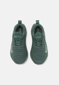 Zelene atletske tenisice s teksturiranim pletivom, ravnim vezicama i petljom za izvlačenje. Na bočnim stranama nalazi se bijeli Nike swoosh logo. Lagani dizajn.
