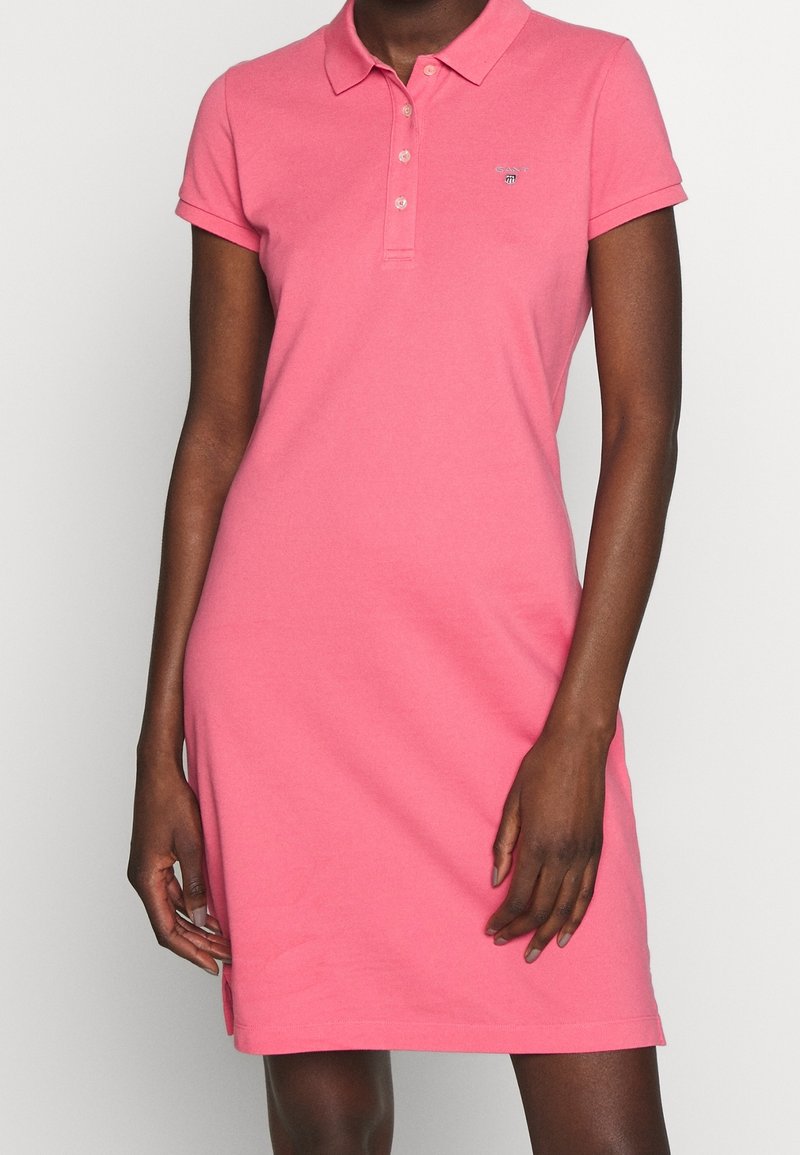Robe polo rose en coton doux, avec des manches courtes, un col, et un subtil brodé logo sur la poitrine.