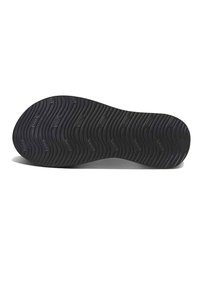 Semelle de chaussure en caoutchouc noir avec une texture ondulée et des motifs de traction. Forme arrondie avec des bords lisses et sans matériel ou accents visibles.
