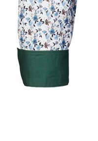 Tessuto a fantasia floreale con fiori blu e marroni su uno sfondo bianco, con un polsino verde scuro uniforme in basso.