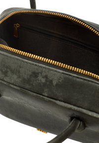 Interno di una borsa in pelle nera con dettagli in zip dorata. Foderata con un tessuto scuro, include una piccola tasca con zip. Forma rettangolare compatta.