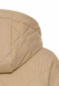 Beige quiltet jakke med stor hætte, glat tekstur og diamantformet syning mønster langs stoffet.