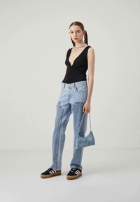 Black plunging v-neck top, light blue jeans, black platform sneakers with white stripes, and a light blue handbag with a chain strap.
