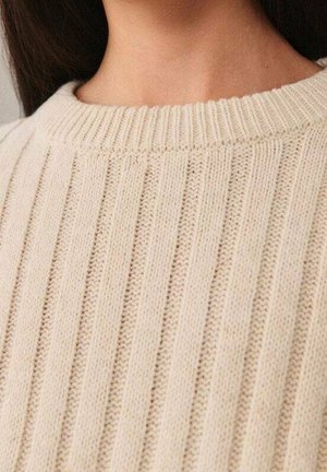 Beige gebreide trui met een geribde textuur en een ronde halslijn. De stof lijkt zacht en lichtgewicht, met gelijkmatig verdeelde verticale strepen.