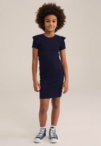 Mornarska rebrasta obleka s kratkimi nabranimi rokavi, prilegajočim krojem, okroglim izrezom in stranskim oznakami, v kombinaciji z modrimi supergami visoke točke.