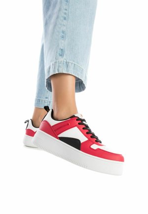 Zapatilla roja y blanca con acentos negros, parte superior de cuero y textil suave, suela blanca gruesa, con cordones negros y detalles de marca.