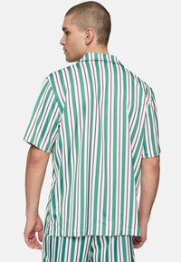 Korte mouwen shirt in groen, wit en paarse verticale strepen. Zachte stof met een ontspannen pasvorm en een klassieke kraag.