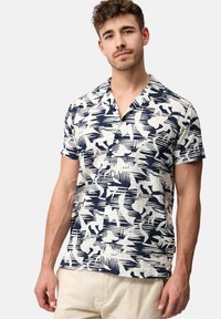 Camisa de manga corta en tejido ligero con un patrón abstracto en azul y blanco; presenta un cuello de tipo camp collar y un cierre frontal con botones.