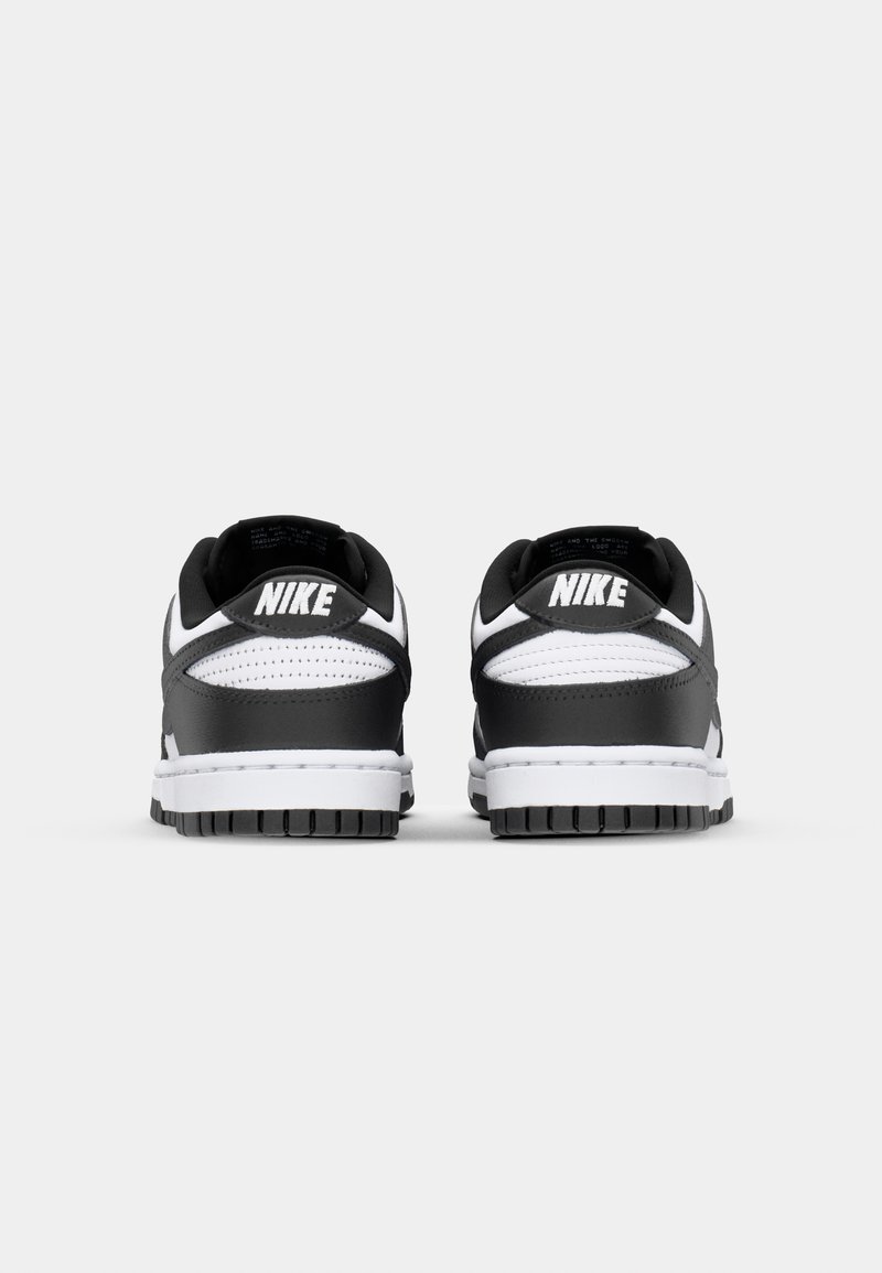 Schwarz-weiße Nike-Sneaker verfügen über ein Lederoberteil, eine perforierte Oberseite für Belüftung und eine strukturierte schwarze Gummisohle.