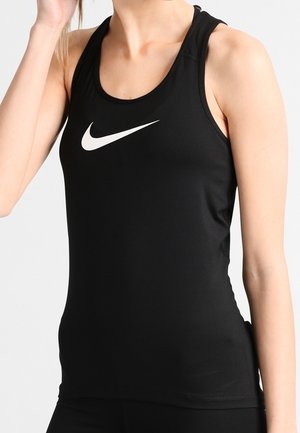 Kobieta ubrana w czarny sportowy top bez rękawów z białym logo Nike na piersi na jednolitym tle.