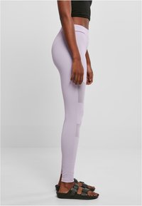Jasnofioletowe legginsy wykonane z elastycznej tkaniny, wyposażone w boczne panele z siateczki dla lepszej wentylacji. Model z wysokim stanem i zwężanymi nogawkami.
