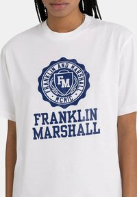 White cotton t-shirt featuring a circular navy blue logo with "Franklin and Marshall" and "MCMC," with large "FRANKLIN MARSHALL" text below.
