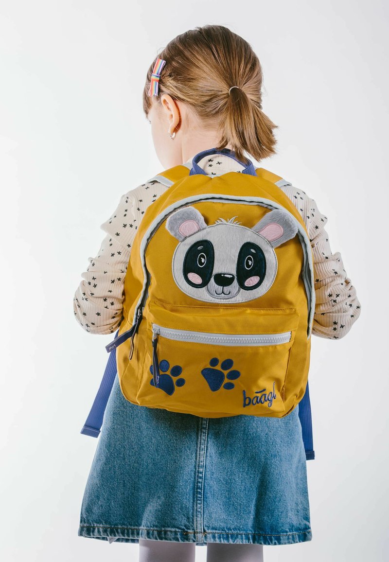 Zaino giallo con faccia di panda, spallacci blu e dettagli a forma di impronta di zampa. Realizzato in tessuto con una tasca frontale con zip.