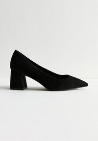 Décolleté neri con tacco a blocco e punta affilata, realizzati in suede. Presentano una texture liscia e un design minimalista.