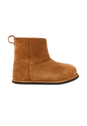 Brun ruskind ankle boot med rund tå, flad sort sål og trækstrop bagpå, vist mod hvid baggrund.