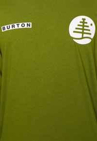T-shirt verde a maniche lunghe con logo Burton bianco e grafica di un albero nella zona sinistra del petto. Tessuto morbido, vestibilità casual.