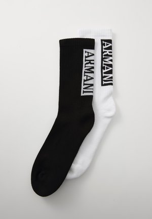 Deux paires de chaussettes mi-mollet, l'une noire et l'autre blanche, avec une texture côtelée et un logo "ARMANI" contrastant en noir sur la section blanche et en blanc sur la section noire.