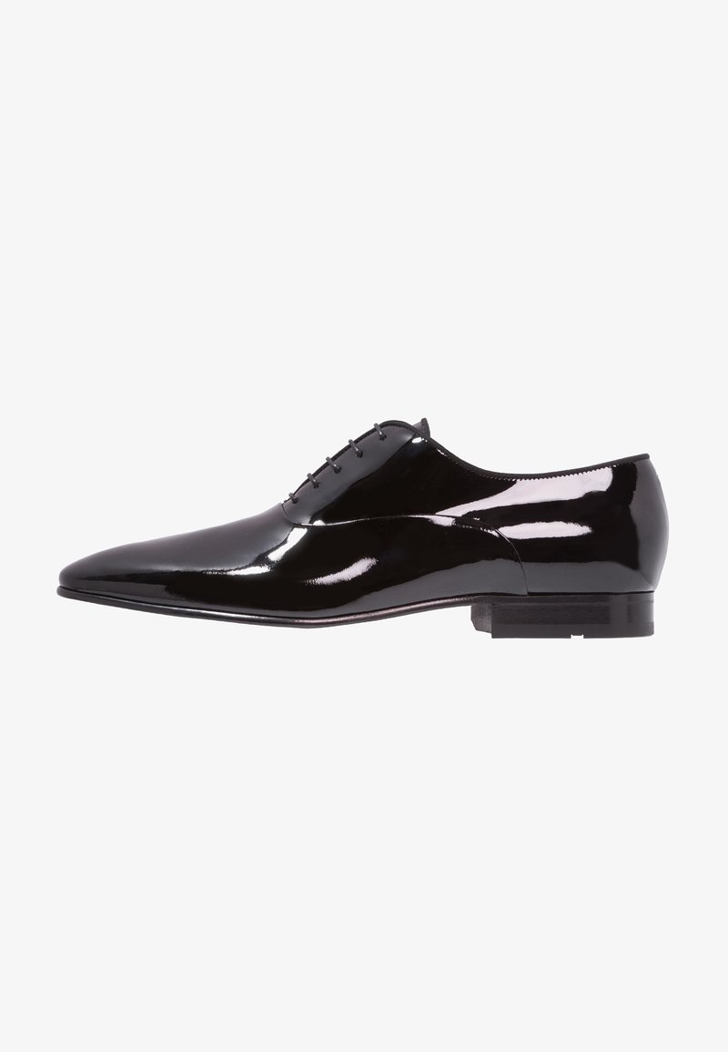 Chaussure habillée pour homme en cuir verni noir à bout pointu, cinq œillets pour les lacets et talon bas empilé, vue de profil.