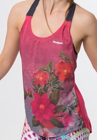 Top a fiori rosso e rosa con un motivo a rombi, con un design racerback e spalline nere a contrasto. Logo del marchio visibile sul davanti.