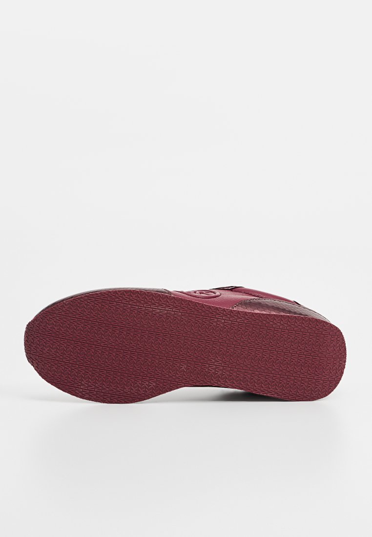 Suola di scarpa color marrone con un dettagliato motivo di battistrada, tacco piatto e bordo della punta arrotondato, fotografata su uno sfondo bianco uniforme.