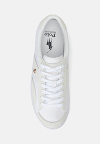 Vit Polo Ralph Lauren sneaker med vita snören, beige mockadetaljer och en liten brun broderad polo-spelare logo på sidan.