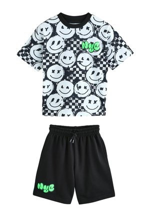 Tricou grafic alb-negru cu modele cu fețe zâmbitoare, asortat cu pantaloni scurți negri care afișează un logo verde „NYC” pe tiv.