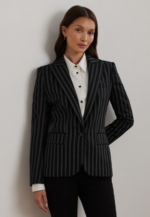 Sort stribet blazer med en skræddersyet pasform, med notch-lapel, frontlomme lukning og to lommer. Bæres over en hvid skjorte med knapper.