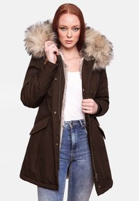Bruine parka met een nep bont capuchon, ritssluiting en drukknoopsluiting, zijzakken en een gevoerde binnenkant. De buitenstof heeft een gladde textuur.